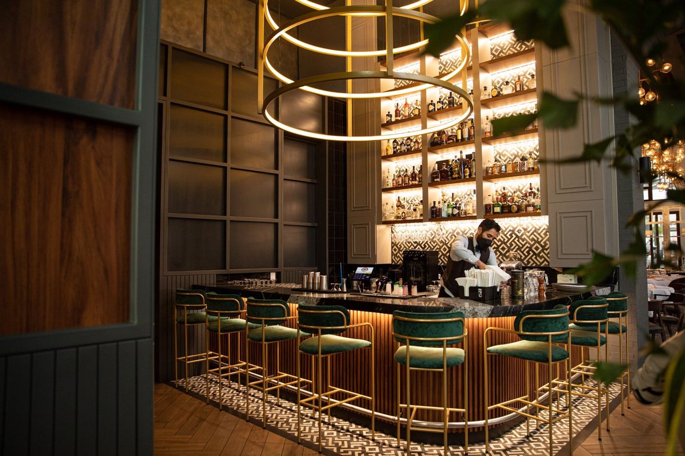 Barra de Izaro Lounge con botellas iluminadas y bancos verdes