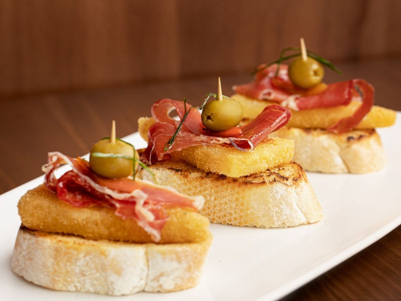 Pintxos con jamón serrano y aceituna sobre pan tostado