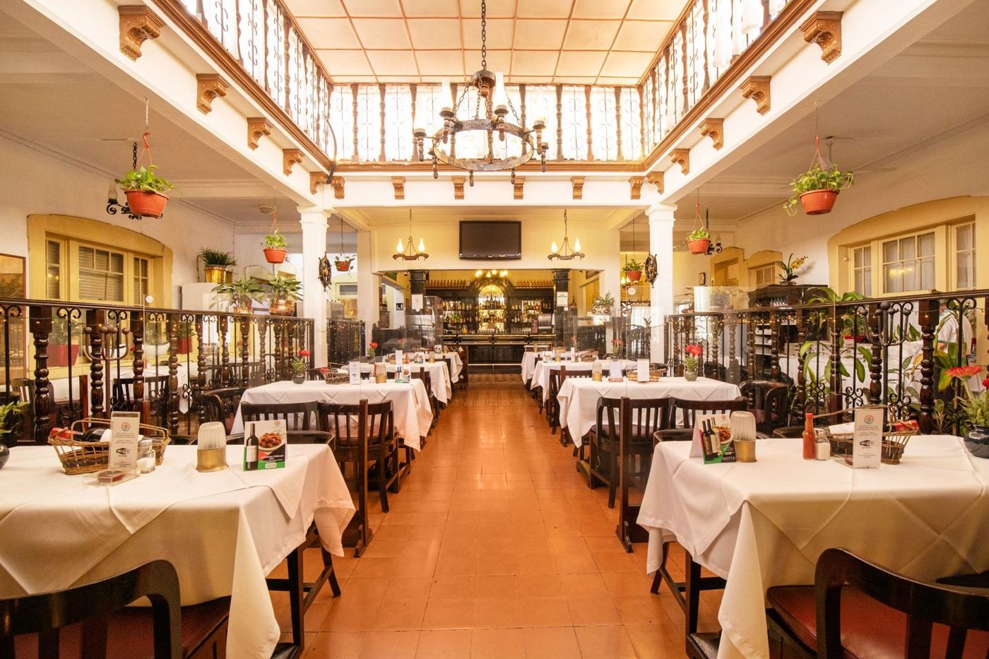 Salón clásico de Altuna con tragaluz, lámparas de araña y mesas con mantel blanco